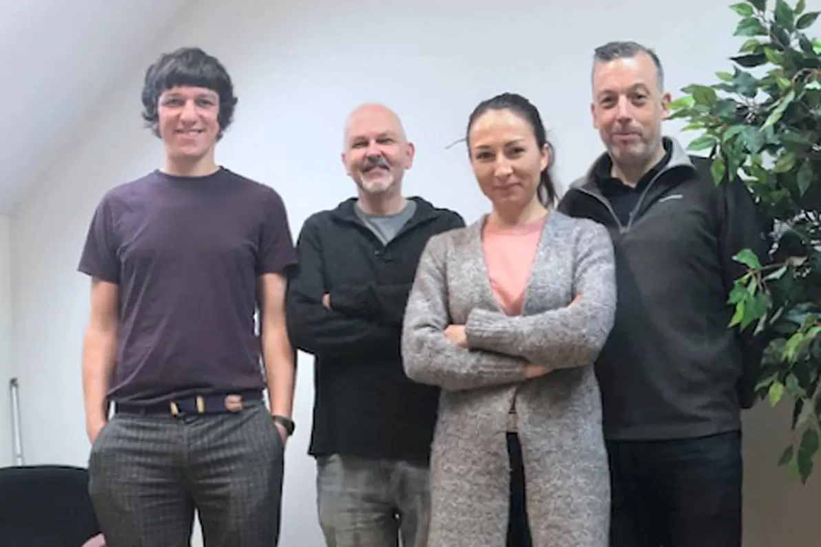 Four colleagues in the Bluesky Ireland office standing on a large floor image of an aerial photograph